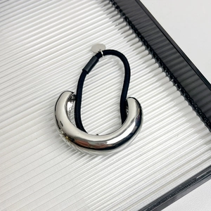Detail of silver U-shaped metal hair cuff with elastic band on clear acrylic tray