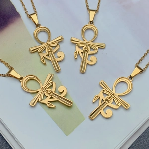 Gold stainless steel Ankh and Eye of Horus cross necklace set on an artistic background