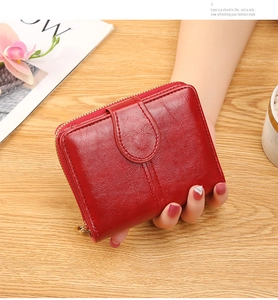 Close-up of glossy wine red wallet featuring smooth oil wax leather texture and U-shaped buckle