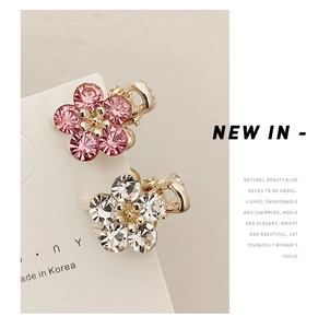 Macro shot of small crystal flower hair claws with pink and white petals on gold base
