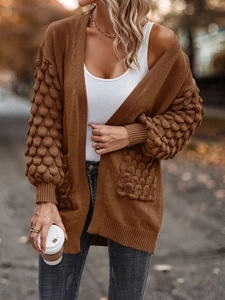 Close-up of brown knit cardigan featuring unique scale-textured cuffs and side pockets