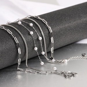 Macro view of layered silver chains with white pearls on a minimalist metal display