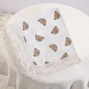 Detail of soft cream cotton baby blanket with brown bear prints and decorative fringe