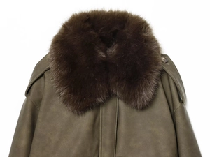 Détail d'une veste vert armée avec un grand col en fausse fourrure et texture mate