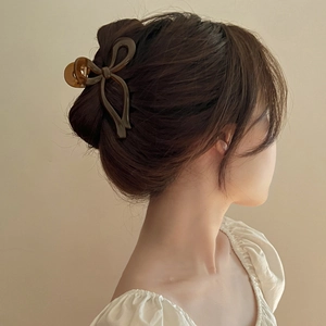 Detail view of an elegant brown amber bow-shaped shark hair claw clip worn in hair