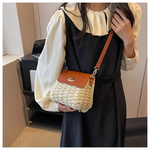 Close-up of woven straw crossbody bag with brown leather flap and golden twist lock