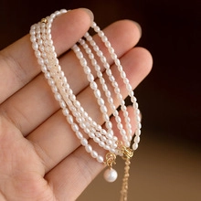 Detail of multilayer freshwater pearl bracelet with gold adjustable chain held in hand