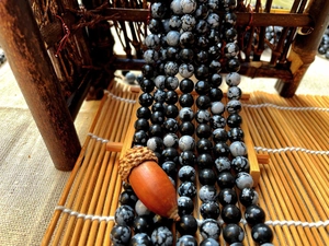 Macro detail of natural snowflake stone beads with grey patterns on a bamboo mat