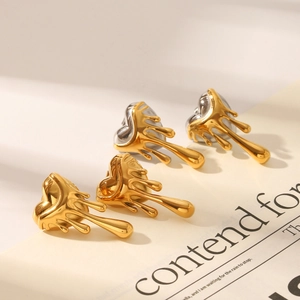 Detailed view of 18K gold lava heart earrings and two-tone silver drop studs on paper