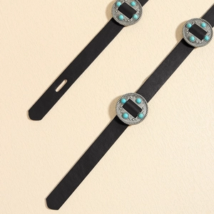 Detail of black leather belt featuring silver round metal buckles with turquoise inlay