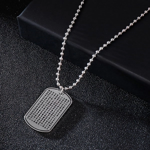 Close-up of silver titanium steel dog tag pendant with engraved lotus sutra text