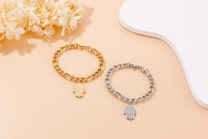 Dettaglio di ciondoli mano di Fatima in oro e argento con eleganti catene Figaro
