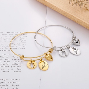 Detail of adjustable stainless steel bracelets with engraved heart and floral charms