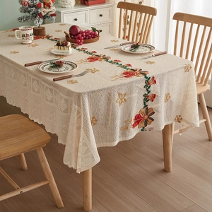 Detail of Christmas beige lace tablecloth with embroidered poinsettia and bell patterns