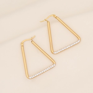 Macro detail of 18K gold-plated triangular earrings with shimmering white zircon stones