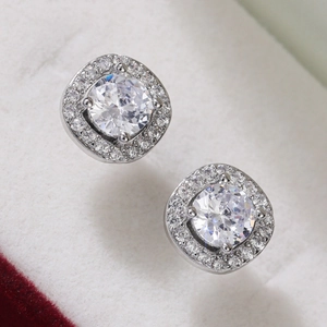 Macro shot of silver halo stud earring with central zircon on white jewelry box