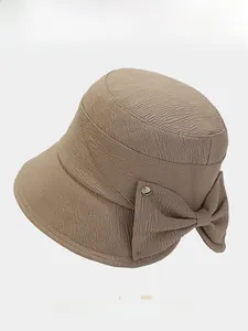 Detail view of khaki bucket hat featuring textured fabric and a decorative bow tie