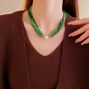 Gros plan du collier multicouche en perles vert émeraude avec fermoir à boules pavé