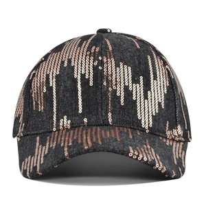 Detail of dark canvas baseball cap featuring golden gradient sequin wave patterns