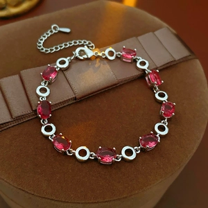 Detailed view of silver bracelet with oval red gemstones on a luxury velvet display