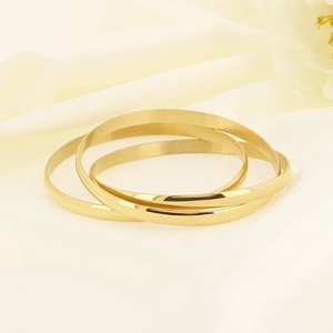 Polished gold interlaced triple-ring titanium steel bangle on white silk background
