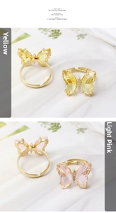 Detailed close-up of yellow and light pink crystal butterfly rings with golden adjustable band