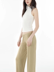 Detail eines weißen, eng anliegenden Stehkragen-Tops kombiniert mit khakifarbener Hose