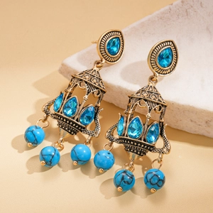 Detailed shot of bohemian gold tassel earrings with blue gemstones and turquoise beads