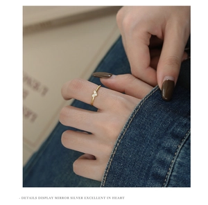 Close-up of a delicate gold heart ring with micro-pave zircons worn on a finger