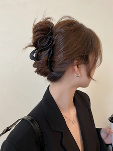 Side view of a large matte black wavy claw clip securing a chic updo for women