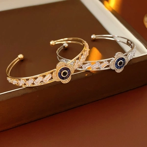 Dettaglio di bracciali rigidi floreali in zircone oro e argento con pietre blu