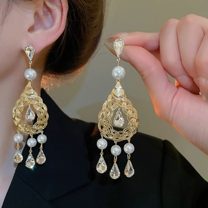 Detail of gold woven drop earrings with white pearls and teardrop crystals for women