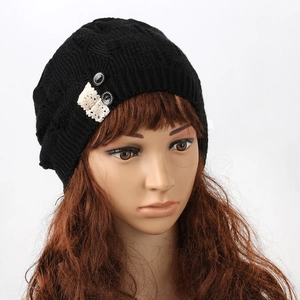 Detail view of women's black knitted beanie with intricate lace and button accents