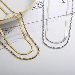 Gold and silver layered snake bone necklace set with flat curb chain on a white background