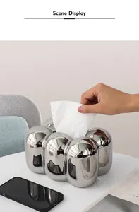 Detail einer Hand beim Herausziehen eines Tuchs aus der glänzend silbernen Taschentuchbox