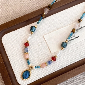 Détail d'un collier de perles colorées avec pendentif en marbre bleu et cadre doré