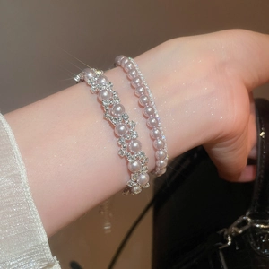 Close-up of stacked pearl bracelets with rhinestones and shimmering silver details