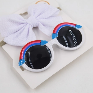 Close-up of kids rainbow sunglasses and white bow headband set on a display card