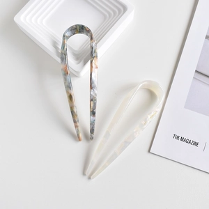 Detailed shot of marbled and pearlescent acetate U-shaped hair forks on a white background