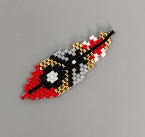 Detailed view of woven beadwork in feather shape with multi-color tassels