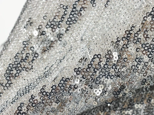 Macro shot of silver sequin fabric detailing with reflective circular metallic texture