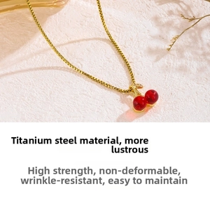 Detail of red cherry pendant with gold leaves on durable titanium steel chain necklace
