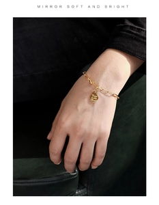 Close-up of gold coin bracelet with Trust in the Lord engraving on a hand wear model
