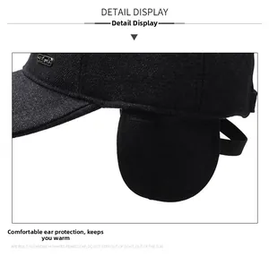Detailed close-up of dark grey winter baseball cap with earflaps and metal sports badge