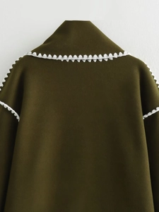 Close-up of olive green wool coat featuring white zigzag lace trim at the shoulder seam