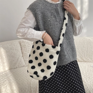 Macro detail of plush faux fur shoulder bag featuring a classic black and white polka dot pattern