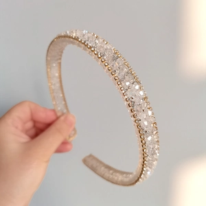 Detailed view of rhinestone headband with gold woven edges and hand-set crystals