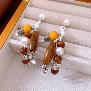 Detailed macro of vintage ethnic earrings with wooden beads and silver floral alloy charms