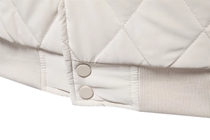 Close-up of diamond quilted jacket hem with ribbed knit cuffs and metal snap buttons