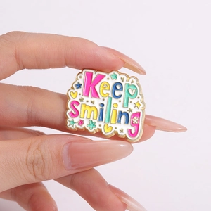 Keep Smiling enamel pin with flowers and stars on a cloud shaped metal base badge